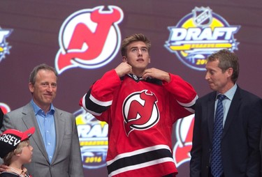 TWELFTH PICK: MICHAEL MCLEOD, NEW JERSEY DEVILS
Michael McLeod puts on his sweater as he stands on stage with members of the New Jersey Devils management team at the NHL draft in Buffalo, N.Y. on Friday June 24, 2016. 
(THE CANADIAN PRESS/Nathan Denette)