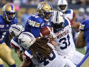 Andrew Harris is met by a pack of Montreal Alouettes on Friday. (KEVIN KING/Winnipeg Sun)