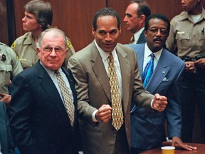In this Oct. 3, 1995 file photo, defense attorney F. Lee Bailey, left, looks on as O.J. Simpson, center, reacts as he is found not guilty of murdering his ex-wife Nicole Brown and her friend Ron Goldman, in court in Los Angeles. (Myung J. Chun/Daily News via AP, Pool, File)