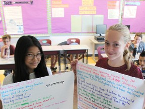 St. Matthew's students Maria Jacinto and Maddy Westfall show off Thursday some of the facts their Grade 7 class has learned about the Fort McMurray wildfires. Their class recently raised $250 for Canadian Red Cross relief efforts by organizing a popcorn fundraiser. Barbara Simpson/Sarnia Observer/Postmedia Network
