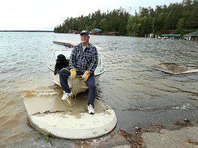 Jim Dixon waits for his son to return with a battery for their boat at the nearly-submerged West Hawk Lake boat launch in Whiteshell Provincial Park on Sunday, June 26, 2016. The road to their cabin is closed due to flooding in the area. (Kevin King/Winnipeg Sun/Postmedia Network)