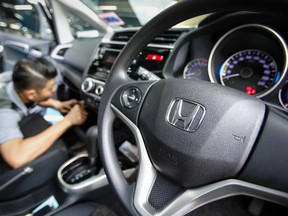 An automotive technician works on a Honda car at a service centre in Kuala Lumpur, Malaysia, Monday, June 27, 2016. A Malaysian woman has died after the airbag in her Honda City ruptured in a minor collision, a safety official said Monday. (AP Photo/Joshua Paul)