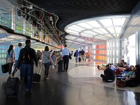 Travellers walk down the walkway between terminals at O'Hare International Airport, Monday, May 30, 2016, in Chicago. (AP Photo/Kiichiro Sato)