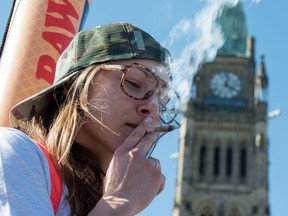 A woman smokes a joint during the annual 420 marijuana rally on Parliament hill on Wednesday, April 20, 2016 in Ottawa. ( THE CANADIAN PRESS)