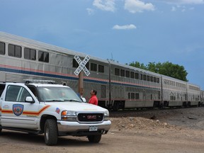 A member of the Fisher's Peak Fire Department watches an Amtrak train after it collided with a minivan at a crossing east of Trinidad, Colo., Monday, June 27, 2016. A four-year-old girl was the only member of her family to survive after their minivan was hit by the Amtrak train at the crossing with a history of problems in southern Colorado, authorities said. (Eric John Monson/The Trinidad Chronicle News via AP)