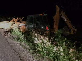 Man arrested early Wednesday asleep at controls of this backhoe, stuck in a ditch. (Police handout)
