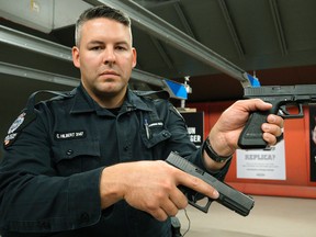 Edmonton Police Service (EPS) Constable Clay Hilbert (Firearms Training Unit) holds two handguns, one real, the other a fake. EPS launched a safety campaign in Edmonton on Wednesday June 29, 2016.