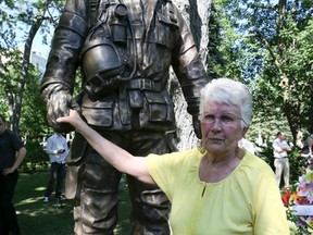 Carole Mitchell, the mother of Jason Churchill, places a flower and grabs the hand of a statue made for her son on Wednesday June 29, 2016. A statue was placed in honour of the Markham firefighter who died from cancer. Veronica Henri/Toronto Sun/Postmedia Network