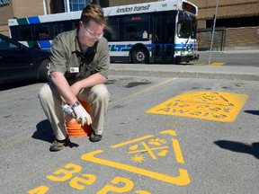 Brent Barr, business director of the Neighbourhood Pet Clinic paints a pet awareness symbol Wednesday on the parking lot of Westmount Shopping Centre. (MORRIS LAMONT, The London Free Press)