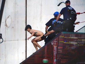 A naked man starts to jump off the staircase ledge above the TKTS Broadway ticket booth in New York's Times Square, Thursday, June 30, 2016. Police said the man, who was shouting about presumptive Republican presidential nominee Donald Trump, was conscious after the jump of about 16 feet off the booth.  (AP Photo)