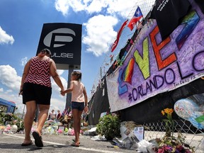 Seven-year-old Kyndall Whitley, with her mother Krisinda Whitley, pay their respects as visitors continue to flock to the roadside memorial at the Pulse nightclub in Orlando, Fla., Wednesday, June 29, 2016. Forty-nine  people were shot and killed by a gunman in the largest massacre in U.S. history, on June 12.  (Joe Burbank/Orlando Sentinel via AP)