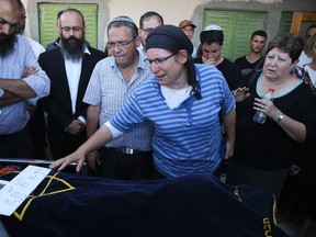 Rina Ariel touches the body of her slain 13 year old daughter Hallel during her funeral inside a Jewish settlement of Kiryat Arba, West Bank, Thursday, June 30, 2016. A Palestinian youth sneaked into a fortified Jewish settlement in the West Bank on Thursday, broke into a home and fatally stabbed Hallel, Israeli-American girl, as she slept in bed before security guards arrived and killed him.(AP Photo/Olivier Fitoussi)