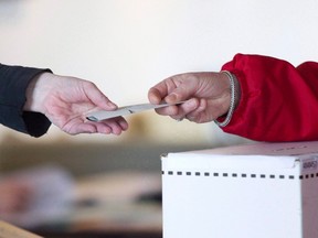 An election official hands back a marked ballot for the federal election in Toronto on May 2, 2011. THE CANADIAN PRESS/Chris Young