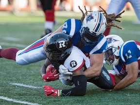 Ottawa Redblacks running back Travon Van is tackled by Montreal Alouettes linebackers Bear Woods and Chip Cox, right, during CFL action in Montreal Thursday, June 30, 2016. (THE CANADIAN PRESS/Paul Chiasson)