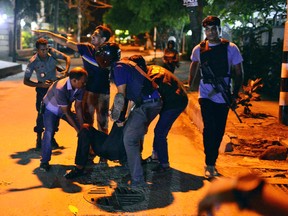 People help an unidentified injured person after a group of gunmen attacked a restaurant popular with foreigners in a diplomatic zone of the Bangladeshi capital Dhaka, Bangladesh, Friday, July 1, 2016. A group of gunmen attacked a restaurant popular with foreigners in a diplomatic zone of the Bangladeshi capital on Friday night, taking hostages and exchanging gunfire with security forces, according to a restaurant staff member and local media reports. (AP Photo)