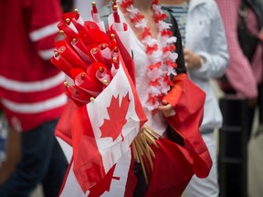 A woman carries Canadian flags for sale during Canada Day celebrations in Vancouver, B.C., on Friday July 1, 2016. THE CANADIAN PRESS/Darryl Dyck
