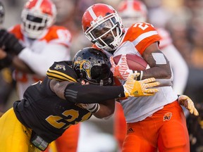 B.C. Lions ball carrier Jeremiah Johnson, right, is tackled by Hamilton Tiger Cats defender Simoni Lawrence during CFL action at Tim Hortons Field in Hamilton on Friday July 1, 2016. (THE CANADIAN PRESS/Geoff Robins)