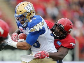 Calgary Stampeders Charleston Hughes, right, tackles Winnipeg Blue Bombers Andrew Harris during CFL action at McMahon Stadium in Calgary, Alta.. on Friday July 1, 2016. Leah hennel/Postmedia