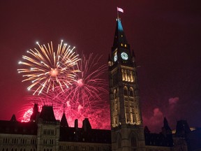 Fireworks light up the sky red behind the Peace Tower during Canada Day celebrations on Parliament Hill on Friday, July 1, 2016 in Ottawa. (Justin Tang/ The Canadian Press)