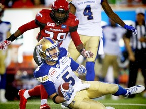 Winnipeg Blue Bombers Drew Willy slides in front of  Jamar Wall of the Calgary Stampeders in CFL football in Calgary, Alta., on Friday, July 1, 2016. (AL CHAREST/POSTMEDIA)