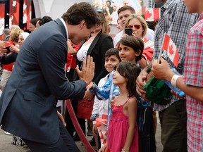 Prime Minister Justin Trudeau high fives children of a Syrian refugee family during Canada Day celebrations on Parliament Hill, in Ottawa on Friday, July 1, 2016. THE CANADIAN PRESS/Justin Tang