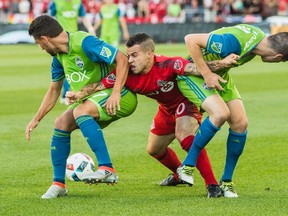 Toronto FC’s Sebastian Giovinco battles for the ball with two Seattle Sounders players during Sunday's game at BMO Field. (THE CANADIAN PRESS)