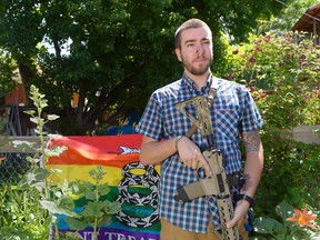Matt Schlentz poses with his Rainbow-Gadsen Flag and AR-15 in his backyard in Salt Lake City,  Wednesday, June 16.  Schlentz is the Pink Pistols Utah chapter President and said Pink Pistols,  a national LGBT pro-gun rights organization, membership has grown from 1,500 to 4,000 since Omar Mateen's June 12 rampage in Orlando, Fla.  (Al Hartmann/The Salt Lake Tribune via AP)