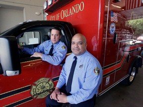In this Thursday, June 30, 2016 photo, Josh Granada, left, and Carlos Tavarez, the first paramedic-firefighters to respond to the Pulse nightclub shooting, stand by their emergency vehicle at their fire station in Orlando, Fla. They made five trips with 13 victims to a hospital emergency room just a few blocks away the evening of the shooting.  (AP Photo/John Raoux)