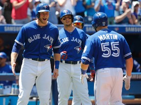 Blue Jays outfielder Michael Saunders, left, and shortstop Troy Tulowitzki (middle) greet Russell Martin after his home run during MLB play against the Cleveland Indians in Toronto Sunday. (Michael Peake/Toronto Sun/Postmedia Network)