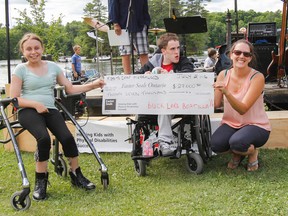 Camp Merrywood kids Keirra MacLeod, left, and Robbie Lovett, along with Krista LeClair of Easter Seals Ontario, accept a cheque for $27,000 raised by the Buck Lake Boatilla. (Julia McKay/The Whig-Standard)