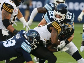 The Toronto Argonauts defence swarms a Hamilton Ticats ball carrier during CFL action at BMO Field. (Postmedia Network file photo)