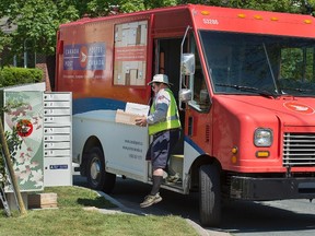 A Canada Post employee fills a community mail box in Dartmouth, N.S. on Thursday, June 30, 2016. Canada Post and the Canadian Union of Postal Workers have been in negotiations since December for its 50,000 delivery and plant employees. The workers are in a legal strike or lockout position as of Saturday if an agreement isn't reached. (THE CANADIAN PRESS/Andrew Vaughan)