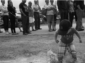 On Canada Day, my son Grayson, 2, splashes in a puddle while the locals wait in line at the annual Seaforth Firefighters' Breakfast.(Shaun Gregory/Huron Expositor)