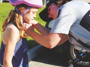 RCMP Constable Stephanie Leduc (r.) checks the helmet on a student from St. Anthony School to make sure it is fitting properly. Volunteers also checked out the students’ bikes before taking them on the obstacle course.