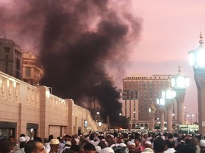 In this photo provided by Noor Punasiya, people stand by an explosion site in Medina, Saudi Arabia, Monday, July 4, 2016. State-linked Saudi news websites reported an explosion Monday near one of Islam's holiest sites in the city of Medina, as two suicide bombers struck in different cities. (Courtesy of Noor Punasiya via AP)