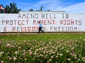 Pastor Brian Coldwell of the Harvest Baptist Academy in Spruce Grove, Alta., is pictured in front of a billboard erected by members of his church on Monday, July 4, 2016. The billboard, which calls for Bill 10 to be amended, was vandalized last week.