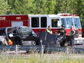OPP officers and a tow truck driver stand next to a pickup truck involved in a three-vehicle collision on the eastbound Highway 401 between Sir John A. Macdonald Boulevard and Sydenham Road in Kingston on Tuesday, July 5, 2016.