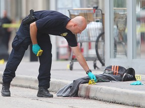 A Winnipeg Police forensics officer places evidence markers near blood stained clothing following a homicide in front of the MTS Centre in Winnipeg, Man. Tuesday July 05, 2016.
Brian Donogh/Winnipeg Sun/Postmedia Network