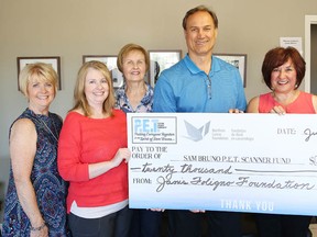 Mike Foligno, of the Janis Foligno Foundation, makes a $20,000 donation to Tannys Laughren, right, executive director of the Northern Cancer Foundation, and members of the Sam Bruno PET Scan Committee on June 29. (John Lappa/Sudbury Star)