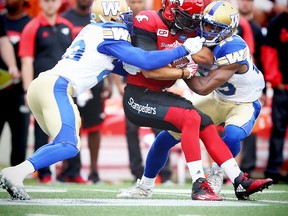 Calgary Stampeders Anthony Parker is tackled by Kevin Fogg and Julian Posey of the Winnipeg Blue Bombers last week. (AL CHAREST/POSTMEDIA NETWORK FILE PHOTO)