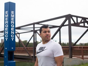 Julien Rivera, 19, poses near the broken emergency phone at Louise McKinney Riverfront Park in Edmonton July 5, 2016. Rivera rescued Maia Stock, 18, when she fell down a river valley embankment and landed unconscious in the water but he was unable to signal for help because the nearby emergency phone was not working. AMBER BRACKEN/ Postmedia Network