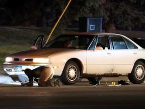 Investigators search a car at the scene of a police involved shooting on Wednesday, July 6, 2016, in Falcon Heights, Minn. A Minnesota officer fatally shot a man in the car with a woman and a child, an official said. (Leila Navidi/Star Tribune via AP)