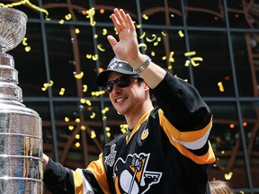 Streamers and confetti fall around Pittsburgh Penguins' Sidney Crosby as he holds onto the Stanley Cup while riding along in the victory parade route in Pittsburgh, Pa., Wednesday, June 15, 2016.  (AP Photo/Keith Srakocic)