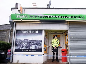 A police officer stands outside the shop where Asad Shah worked in Glasgow, Saturday March 26, 2016. (John Linton/PA via AP)