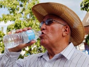 Luke Hendry/The Intelligencer 
Bartolomé Matamoros, of Belleville, takes multiple precautions against the heat: drinking water; wearing a hat, long sleeves and sunglasses; and finding shade outside the Belleville Public Library during a break from his walk Thursday. Doctors also recommend watching yourself and others for signs of heat stress, seeking help quickly when needed.