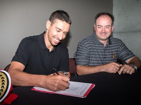 Returning Senators forward Chris Kelly signs his new contract in front of general manager Pierre Dorion yesterday at the Canadian Tire Centre. (Wayne Cuddington, Postmedia Network)