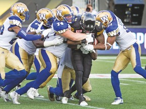 Tiger-Cats running back C.J. Gable is gang-tackled by a host of Winnipeg Blue Bombers last night at Tim Hortons Field. The Ticats fell prey to too many miscues and lost the game 28-24, their second in a row, both at home. (Peter Power, The Canadian Press)