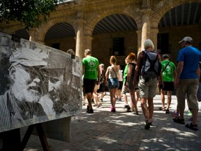 Tourists walk next to an weathered old photo of Ernest Hemingway and Fidel Castro in Havana, Cuba, Monday, March 14, 2016. President Barack Obama will travel to Cuba next Sunday 20. (AP Photo/Ramon Espinosa)