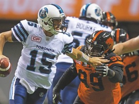Argonauts QB Ricky Ray (15) rolls away from the pressure of Lions’ Jabar Westerman during Thursday’s Toronto win at BC Place. (The Canadian Press).