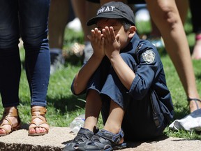 A young boy wears a police uniform as he takes part in a prayer vigil at Thanksgiving Square in Dallas. Five police officers are dead and several injured following a shooting during what began as a peaceful protest in the city the night before. (AP Photo/Eric Gay)